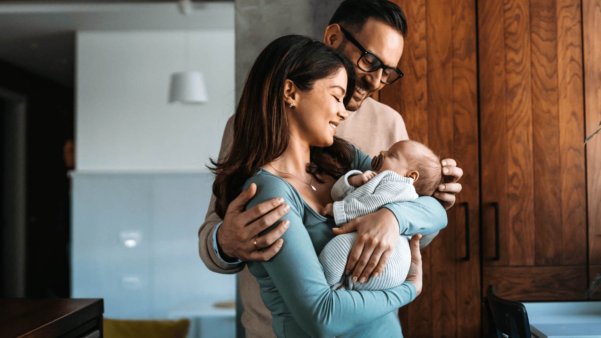 young parents smiling and holding their baby