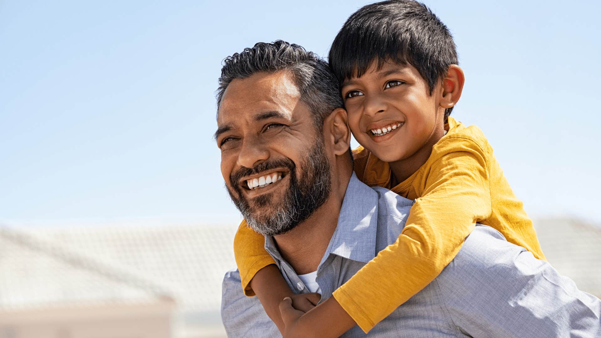 man smiling with young son on his back