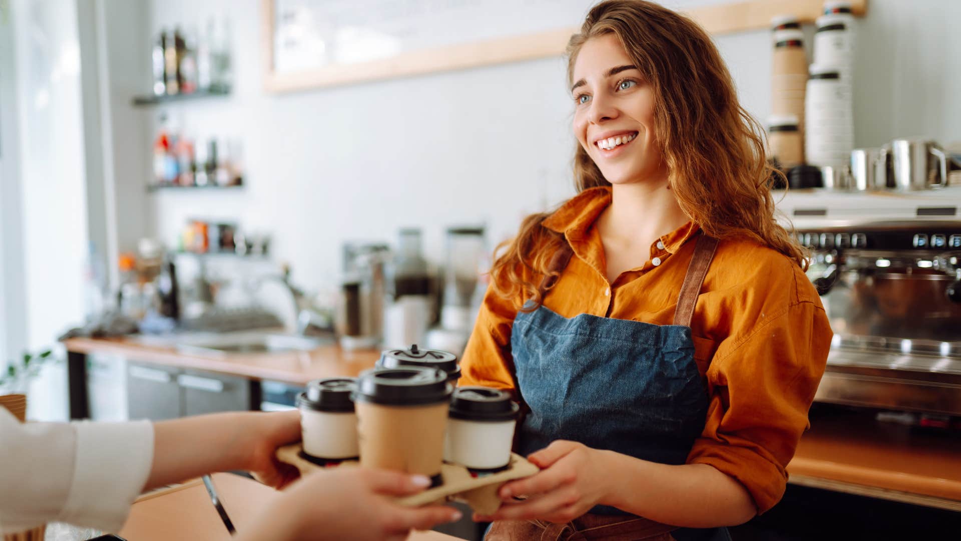 happy barista handing coffees to a customer