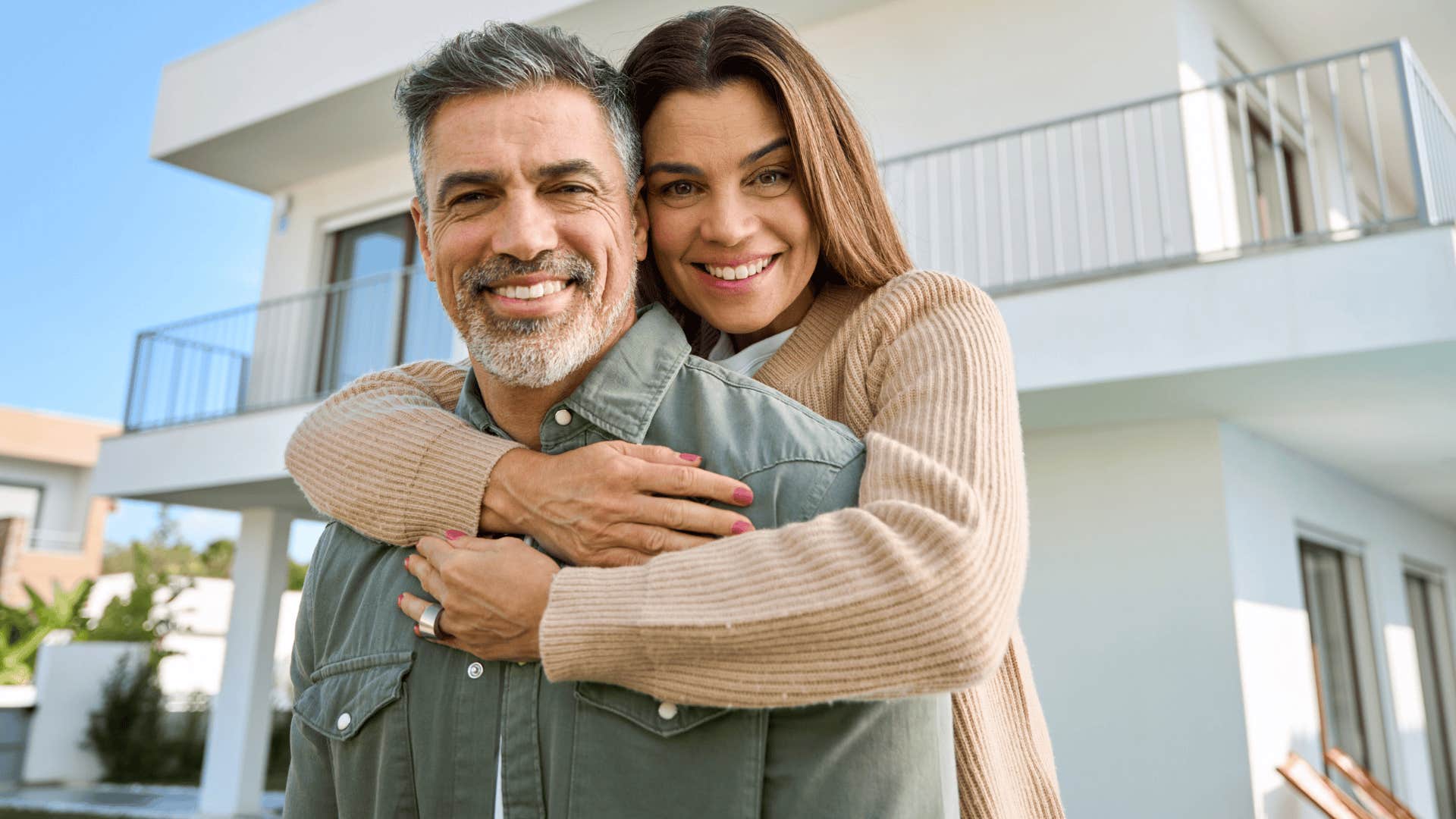 smiling couple standing outside their house