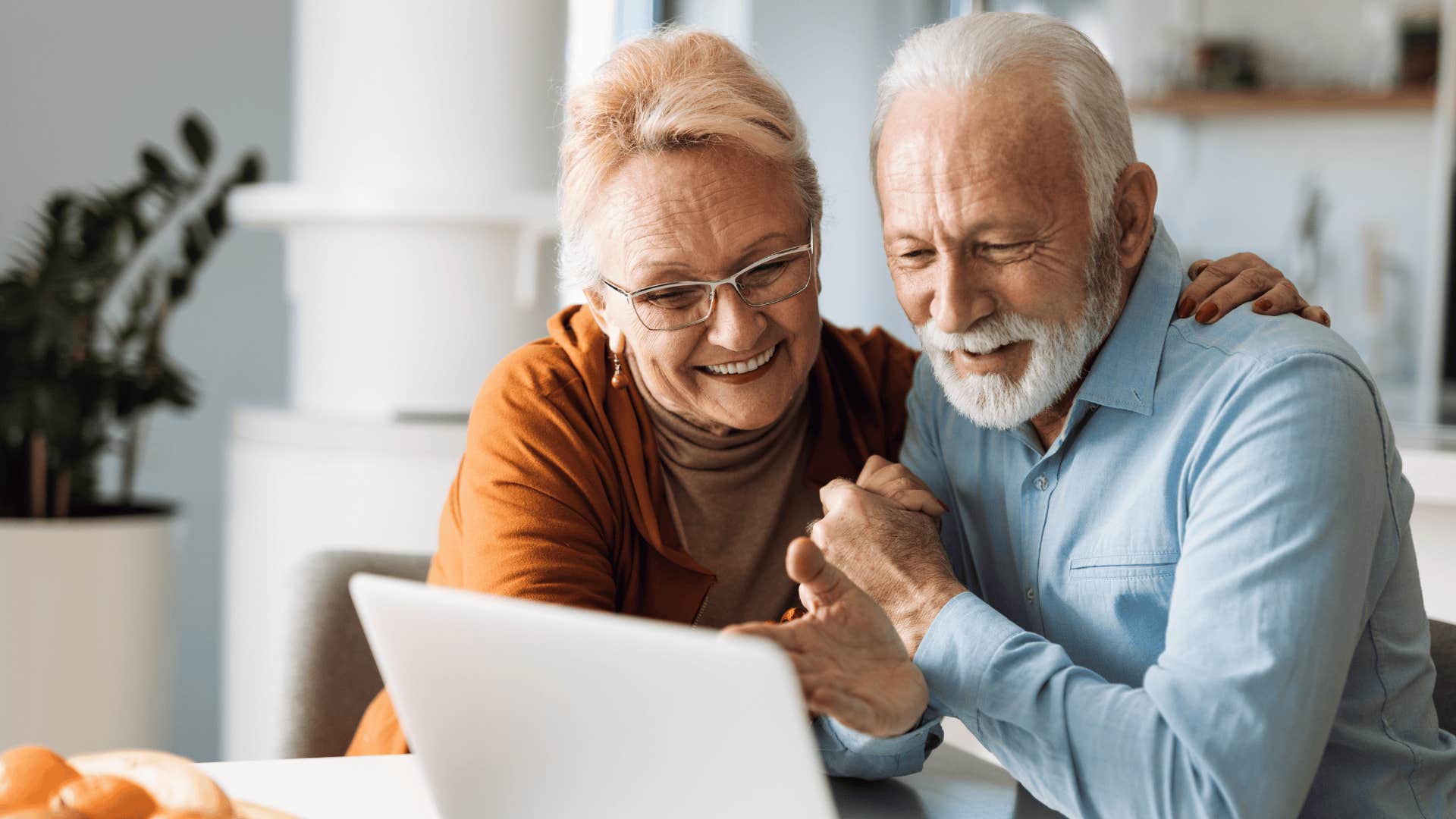older retired couple smiling at laptop