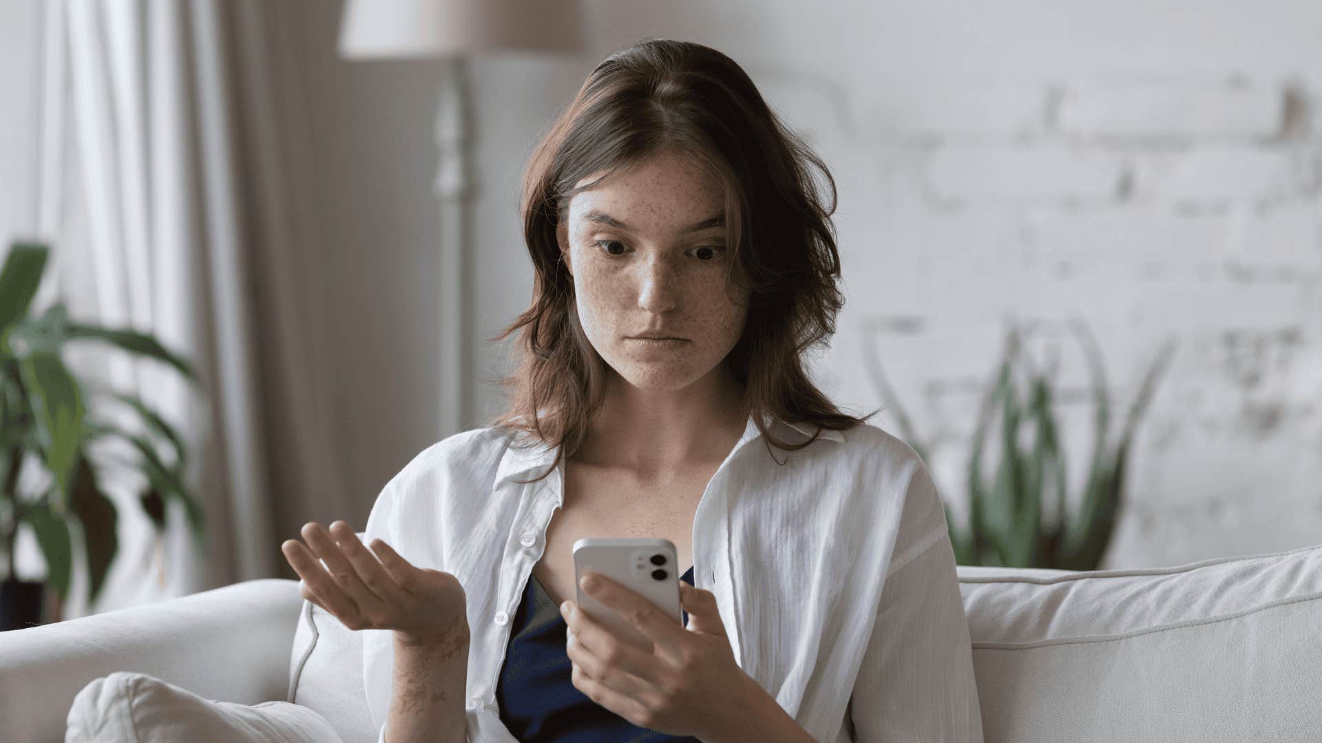 disappointed woman looking at phone after someone canceled plans