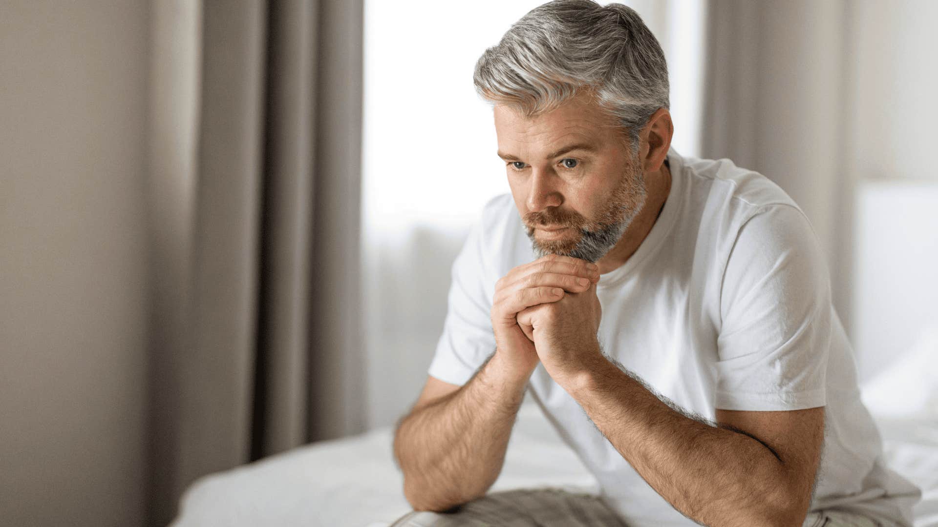 man sitting on his bed after a night of excessive drinking