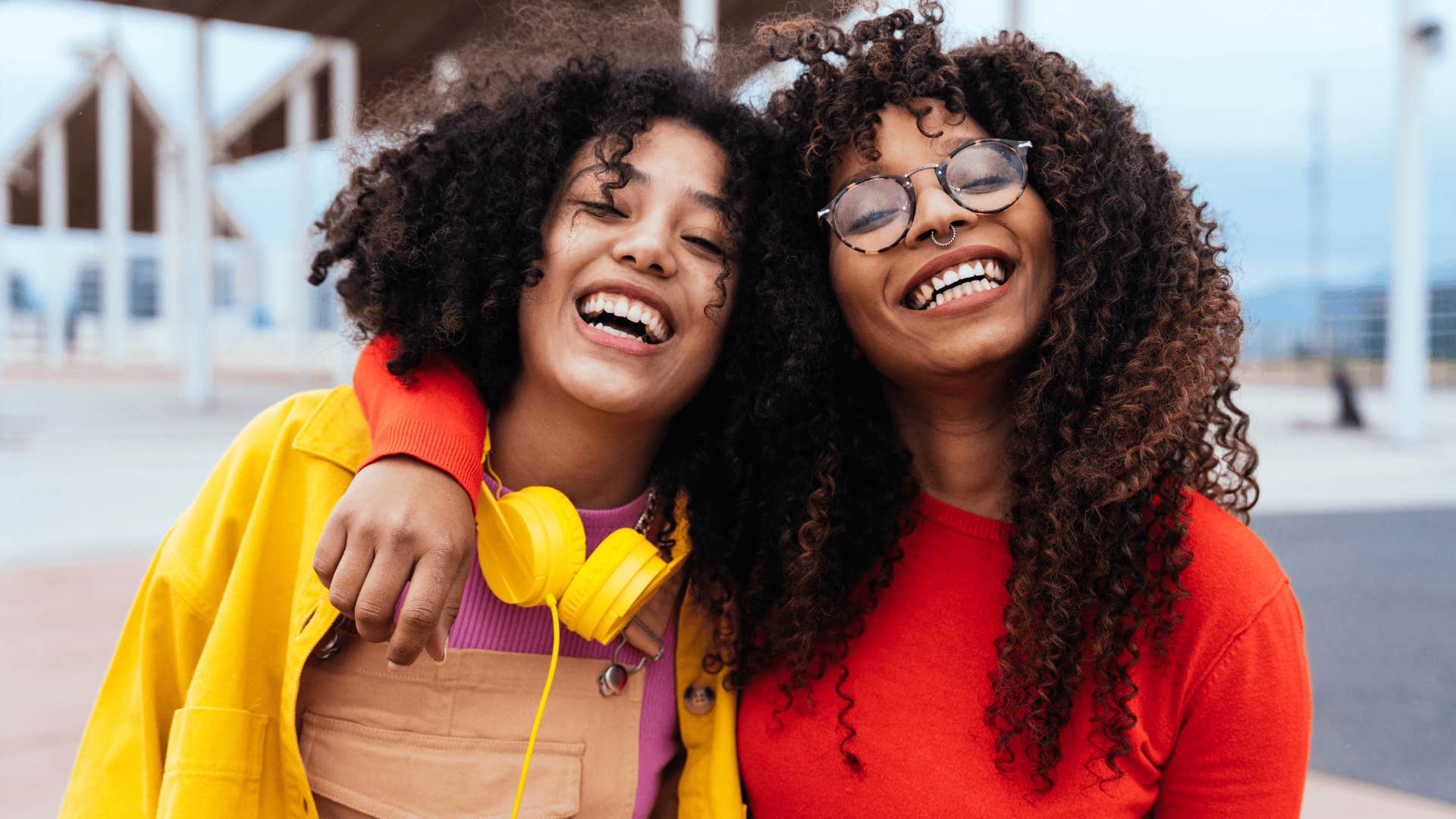 two young women smiling and hugging side by side