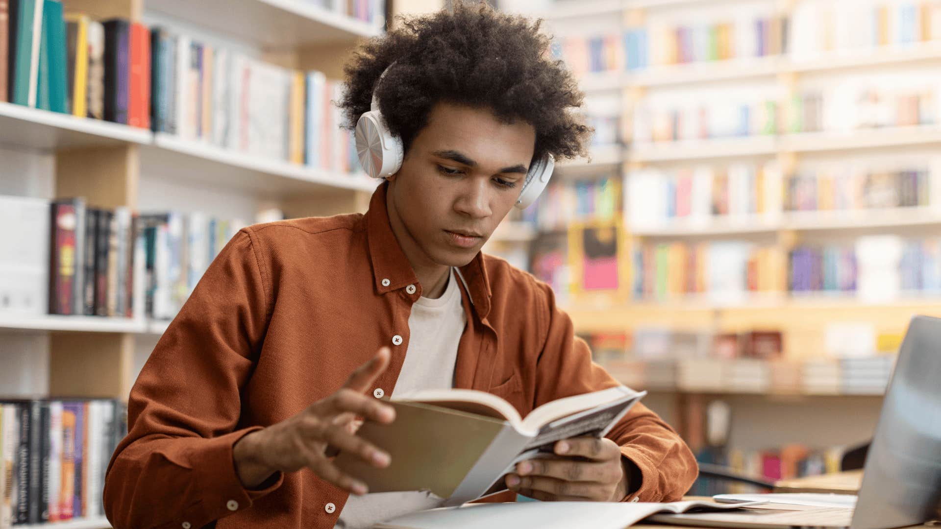 young man reading a book in a library
