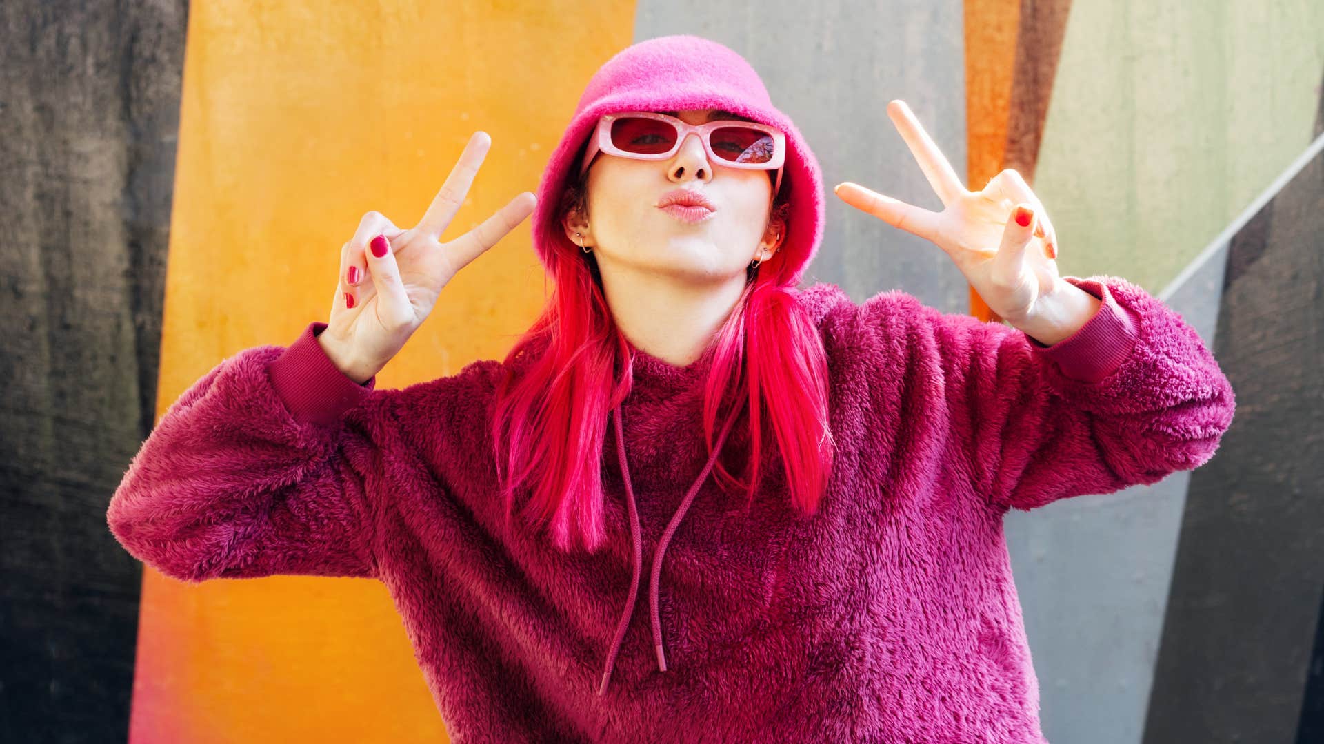 Gen Z woman wearing all pink giving peace signs