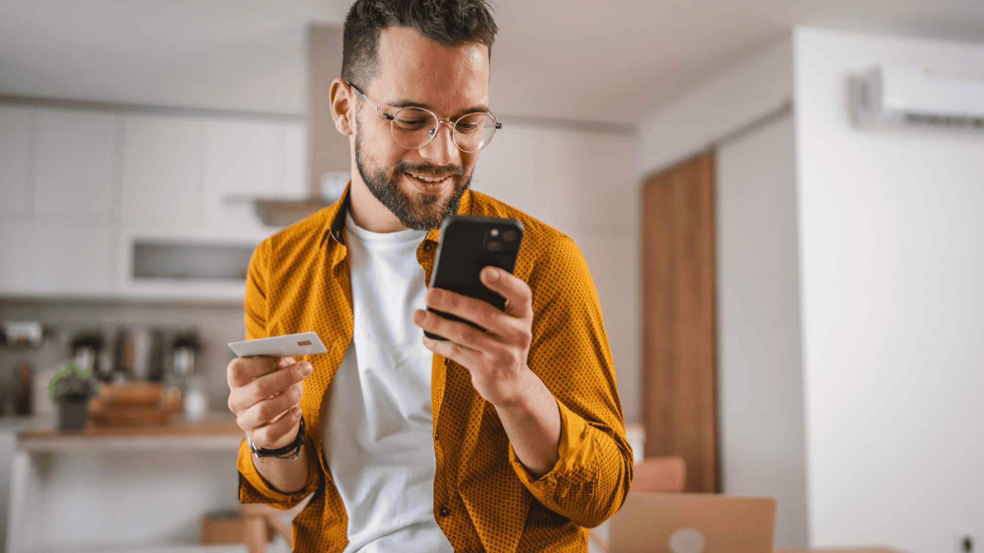 man holding credit card to shop on his phone