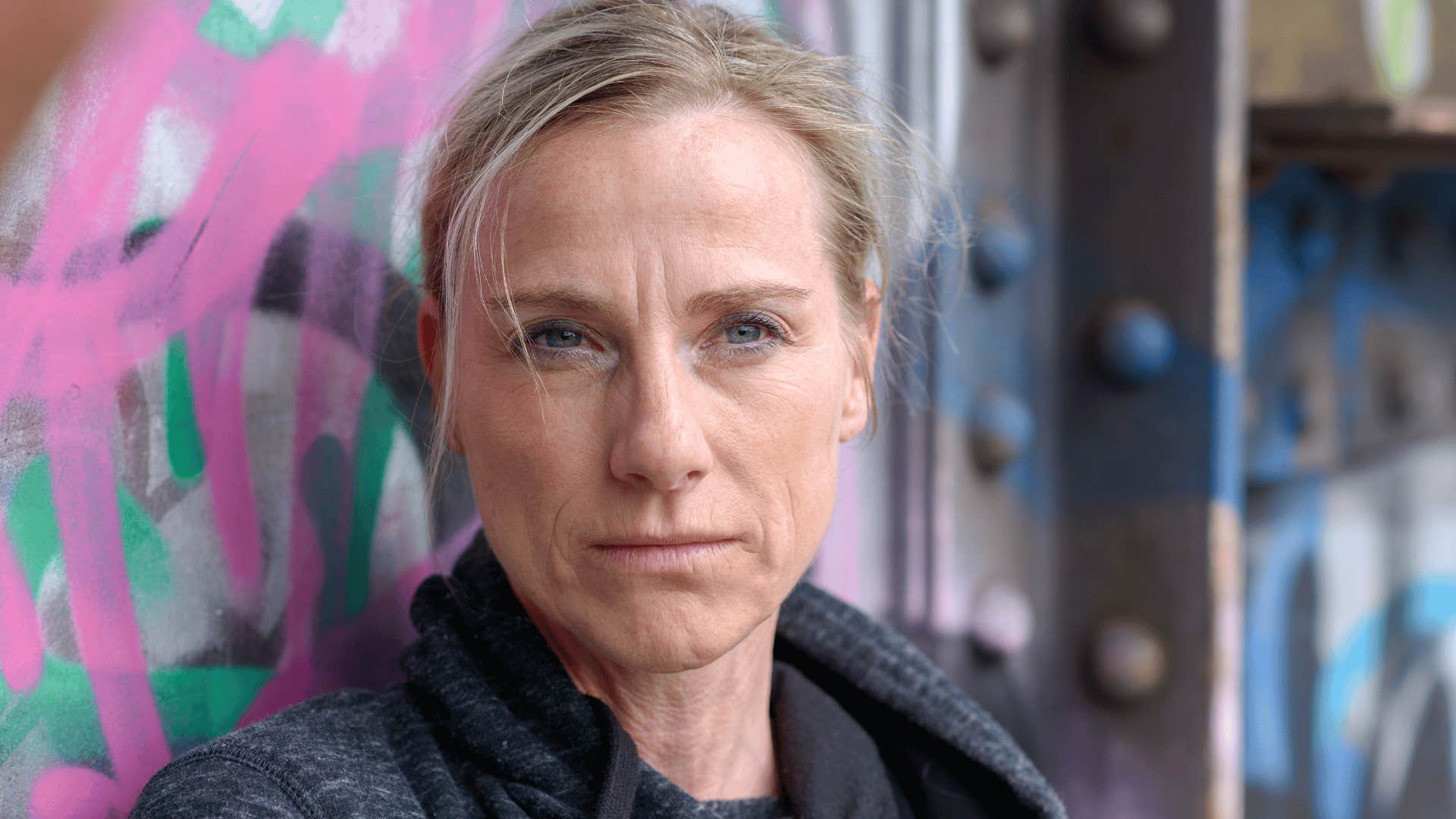 woman standing against wall feeling unsafe