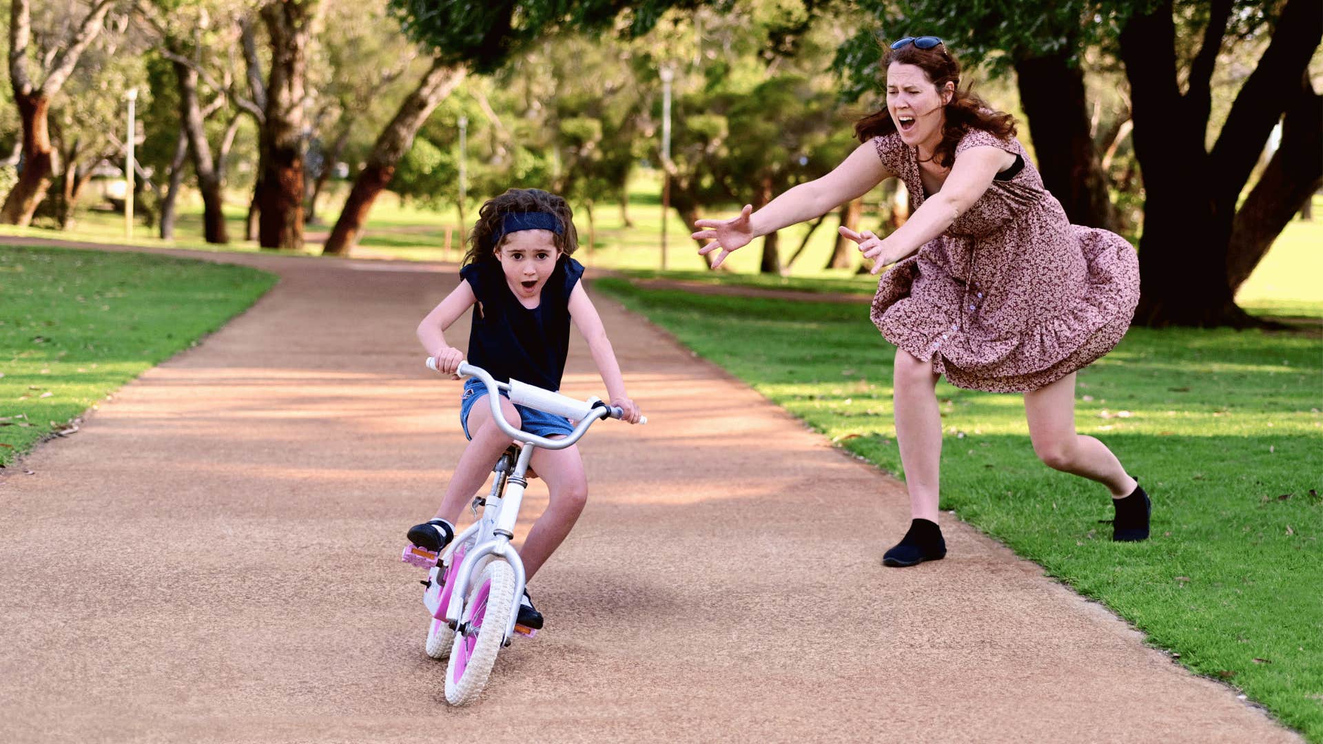 Mother runs after child learning to ride a bicycle