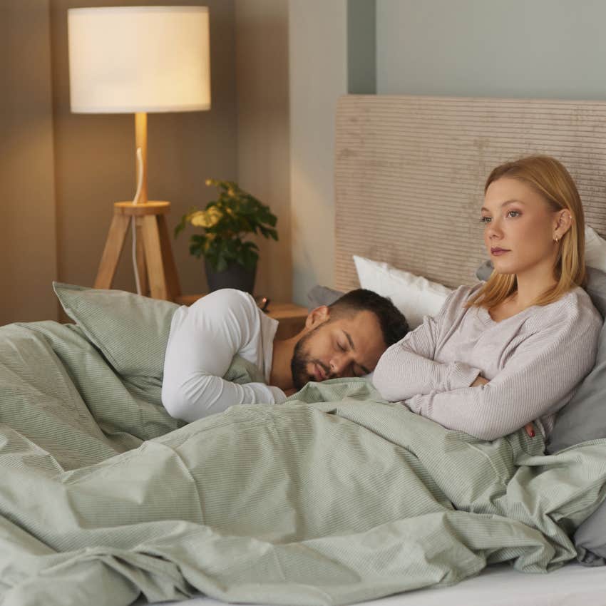 upset woman in bed next to man stuck in toxic relationship