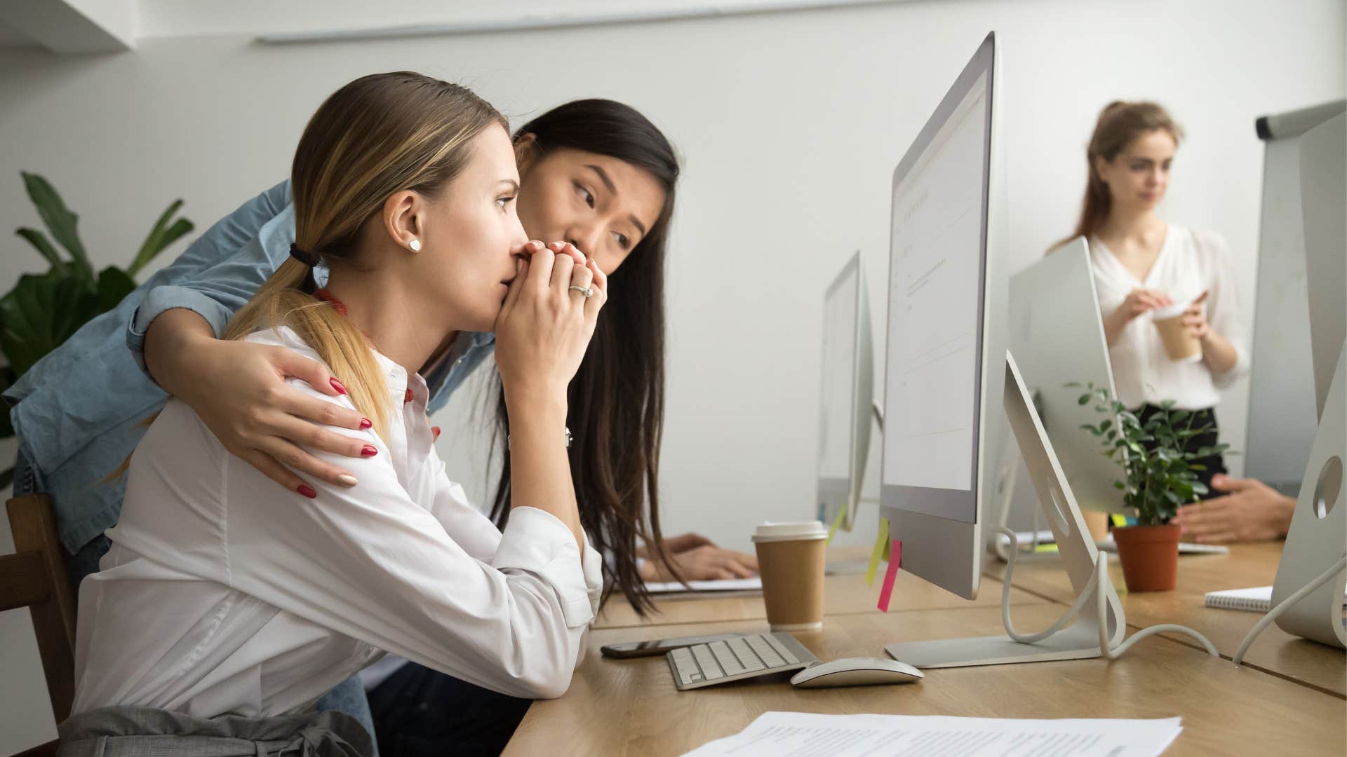 A woman tries to help a procrastinating co-worker on the computer.