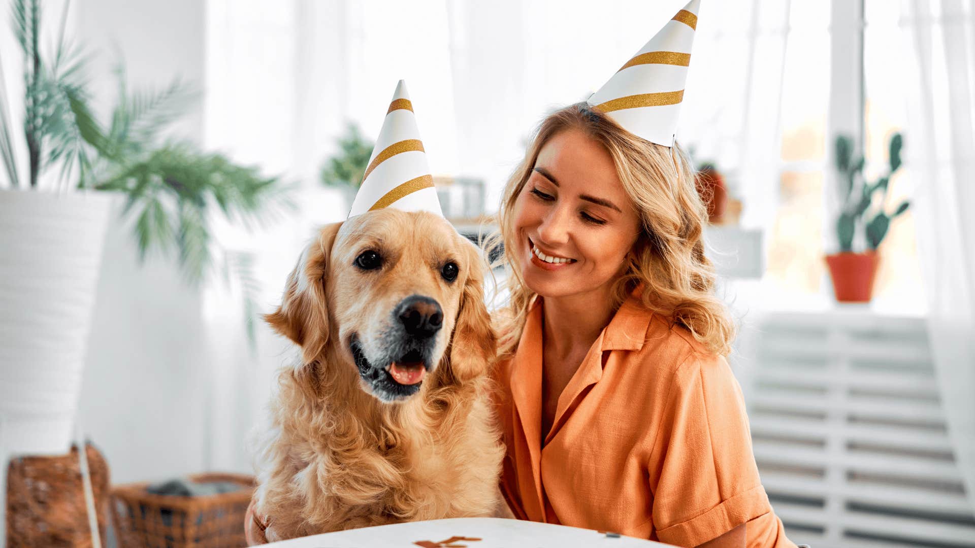 gen z woman smiling with her dog at his birthday party