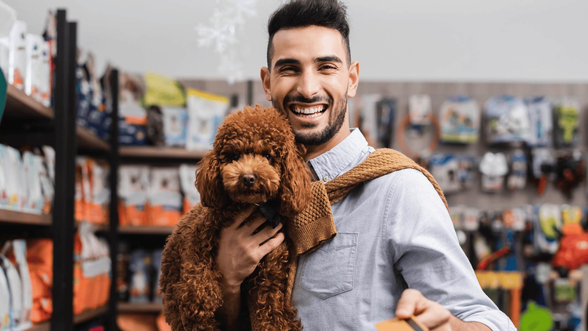 gen z man smiling while holding his service animal dog in a grocery store