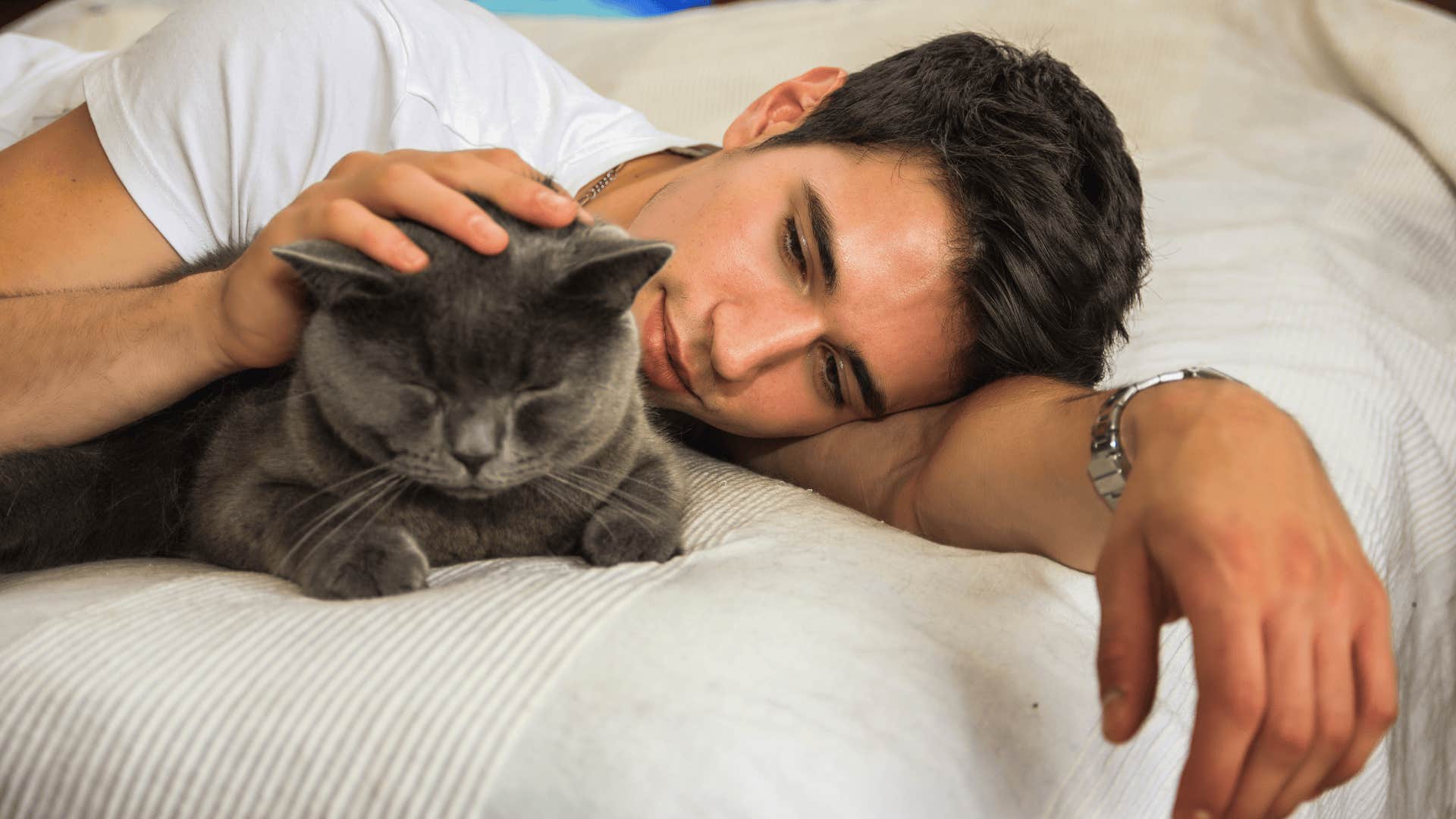 Gen Z man sleeping in the same bed with his cat