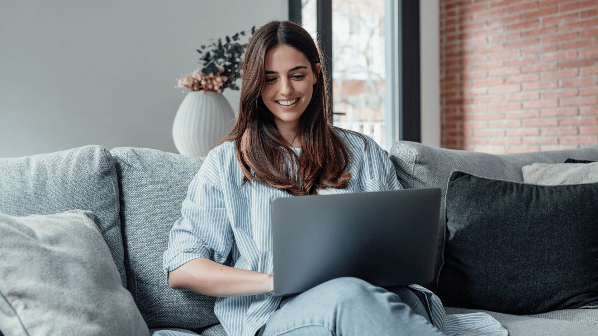 woman working on laptop on couch giving her access to information