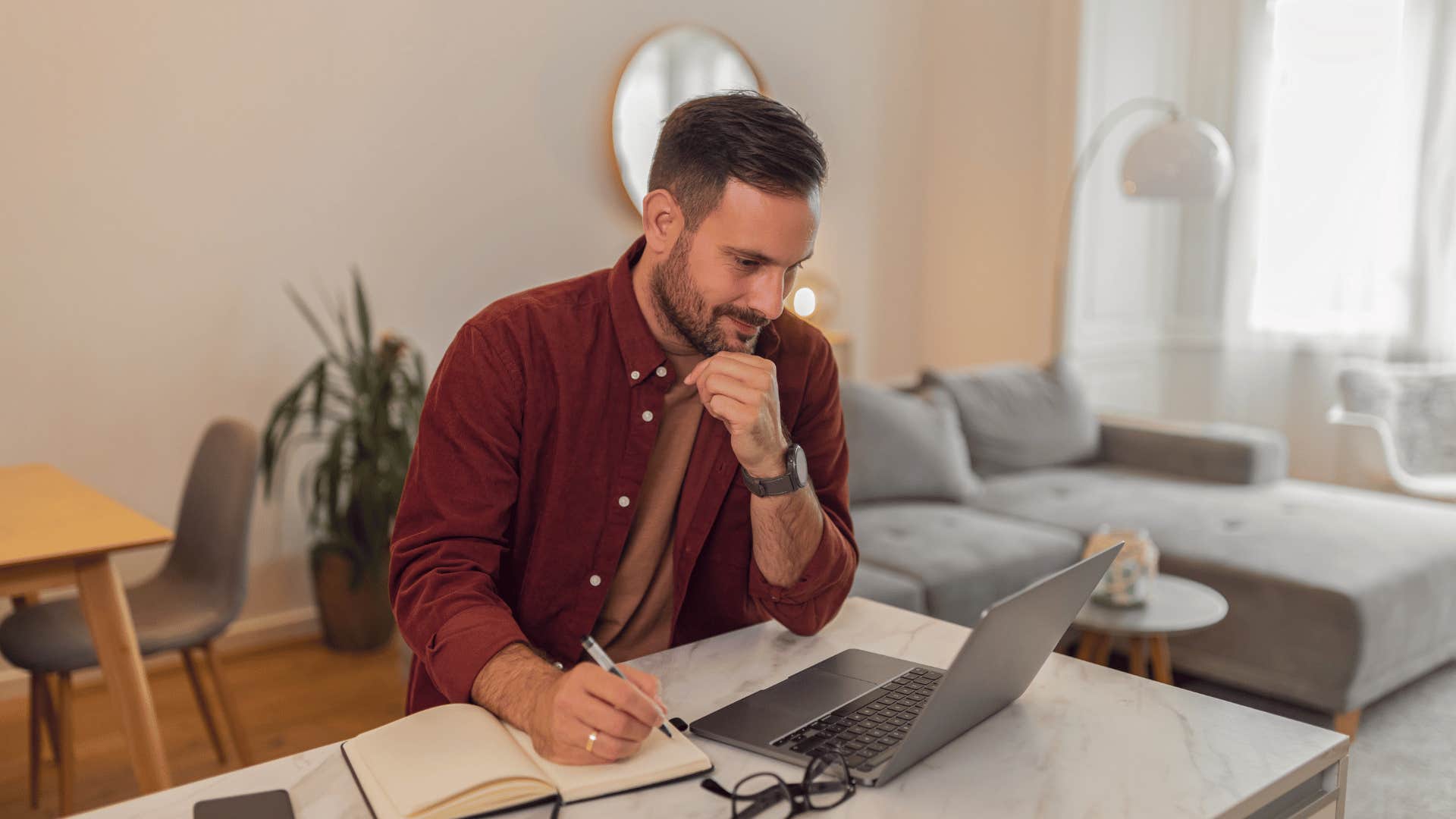 man taking notes and working on laptop access to education
