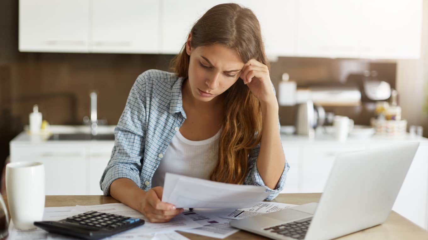 Woman Trying To Pay Off In Debt Reveals How Much She's Saved By Canceling Subscriptions woman looking at bills so she can cancel subscriptions to save money to pay off debt