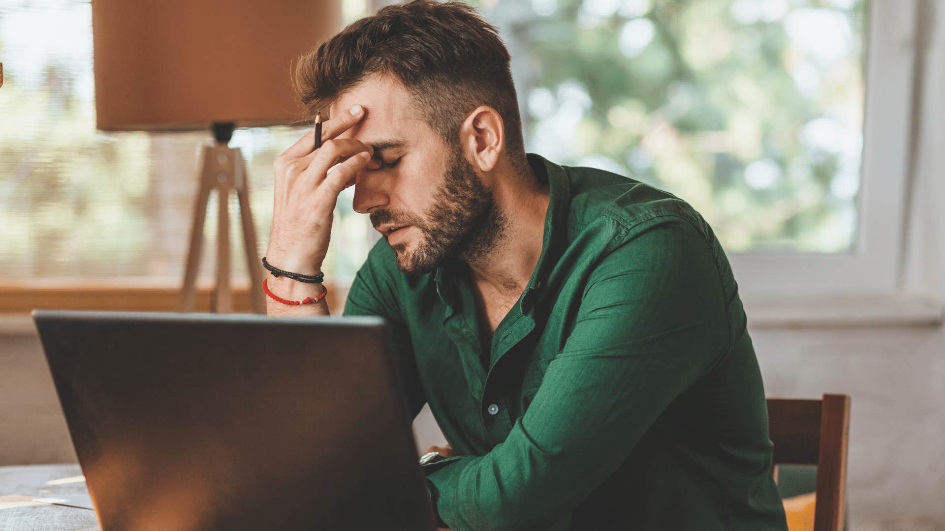 frustrated man sitting in front of his laptop with head in his hands