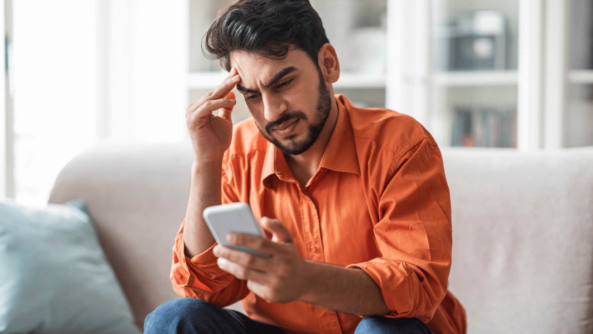 Man looking at his phone being guilted into visiting his family.