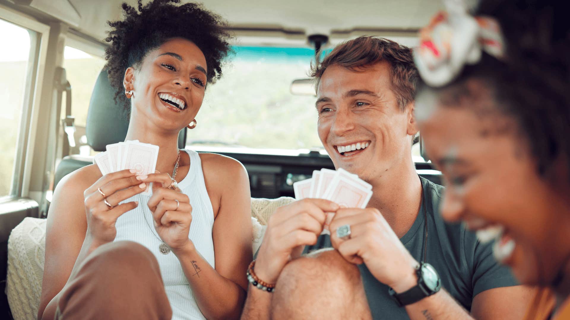 laughing Gen Z friends playing cards in a car