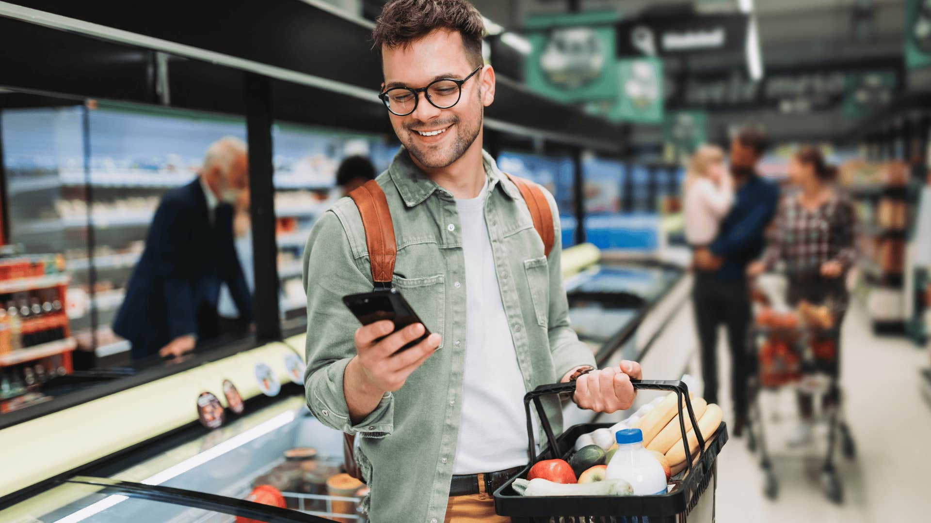 young man texting on his phone in the grocery store