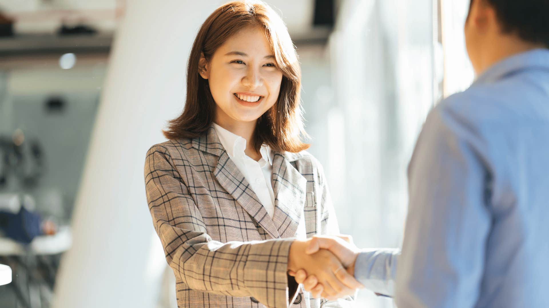 professional woman smiling and shaking a man's hand