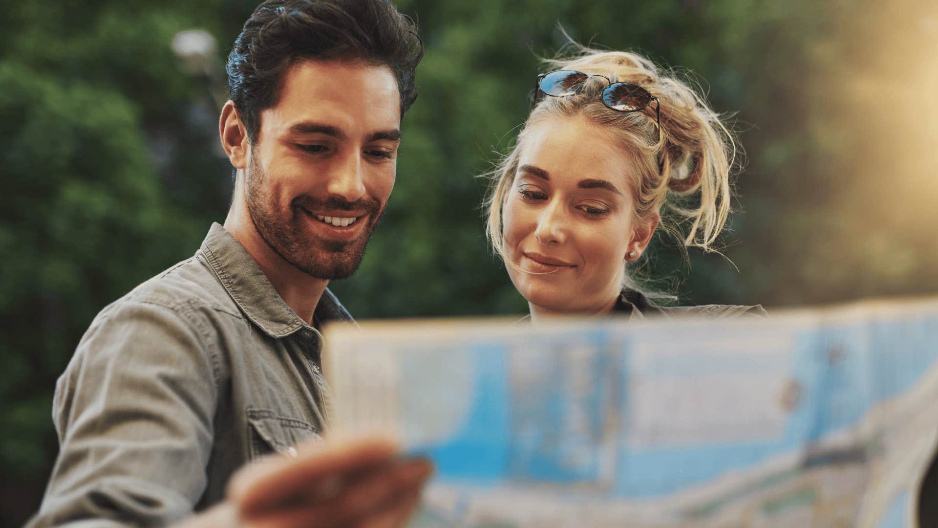 gen z couple smiling trying to read a physical map