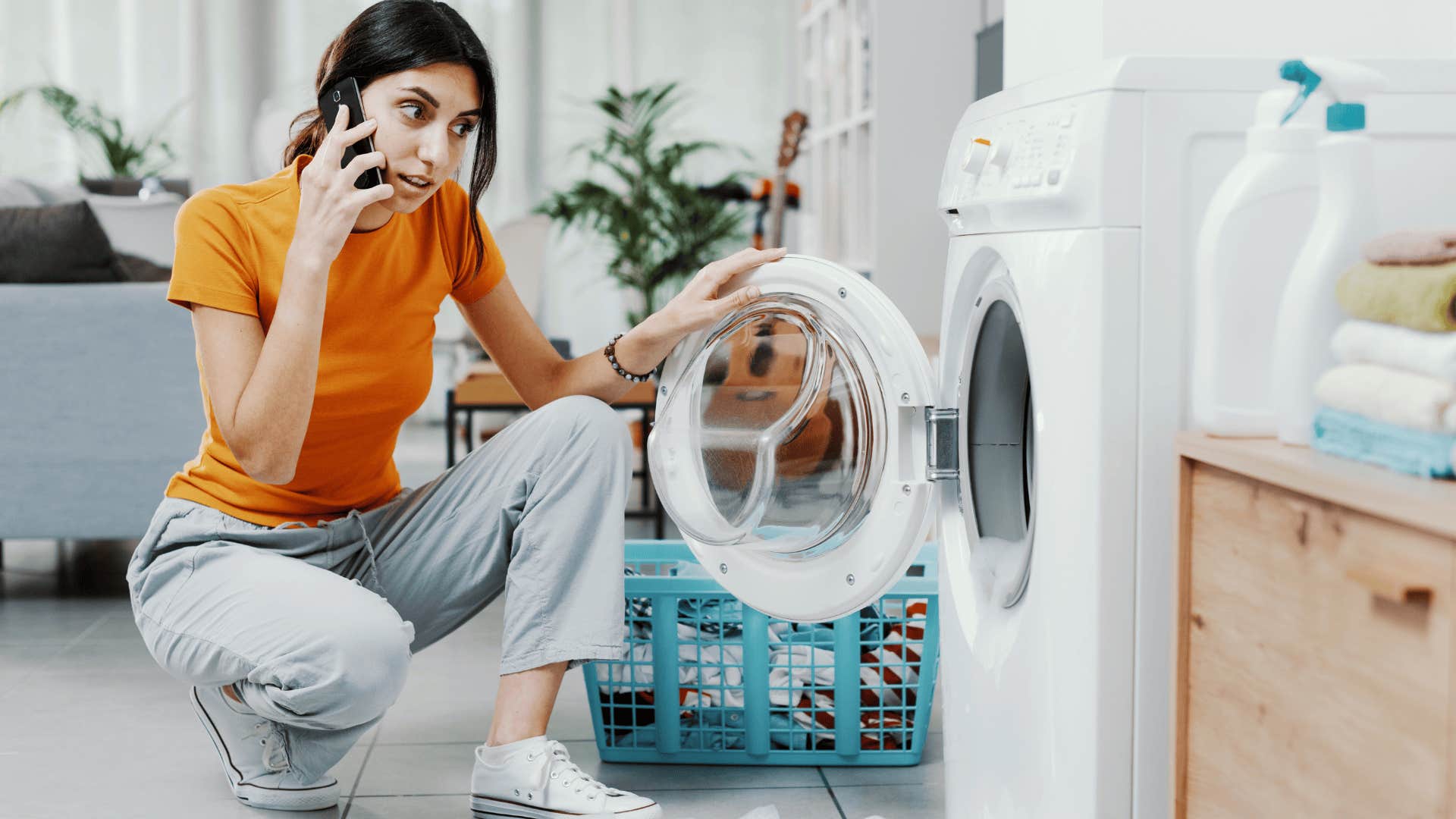 young woman talking on the phone trying to fix washing machine