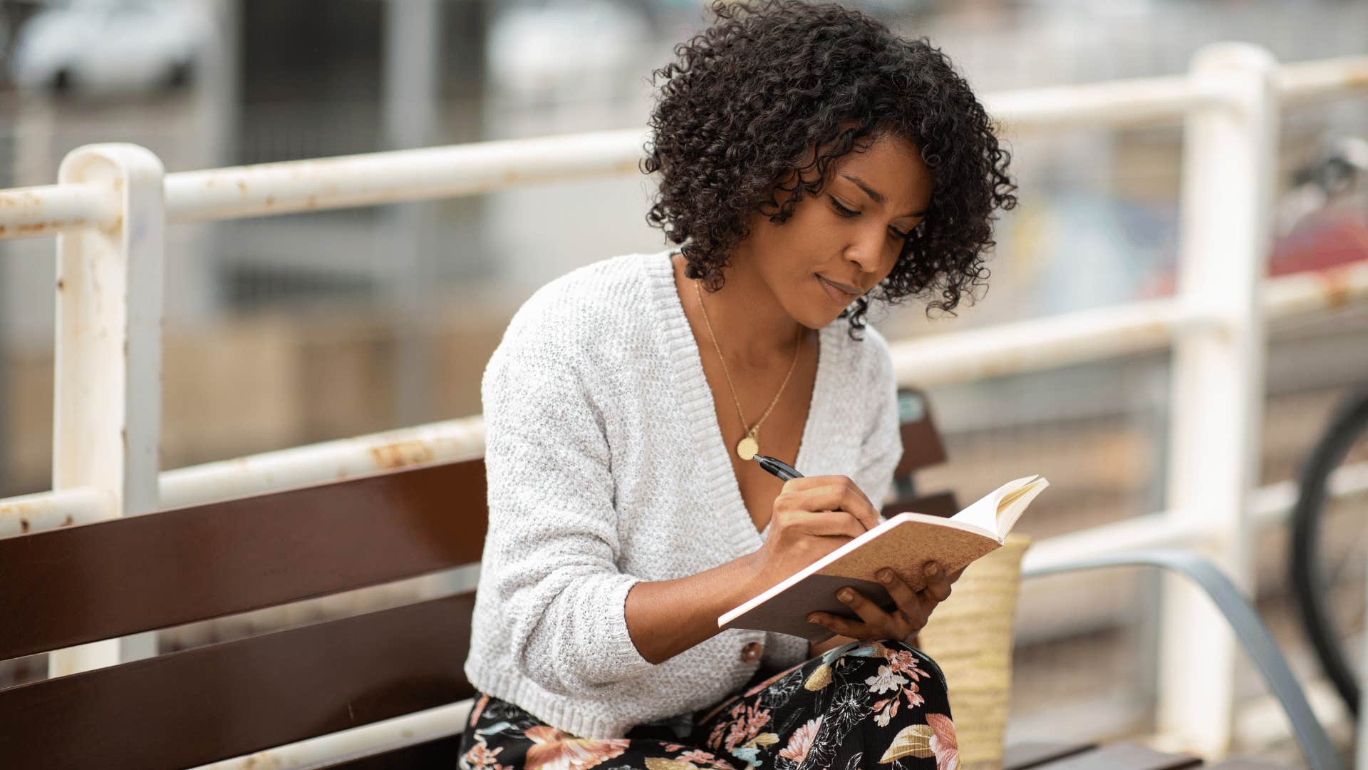 woman showing gratitude everyday as she sits on park bench and writes in her journal