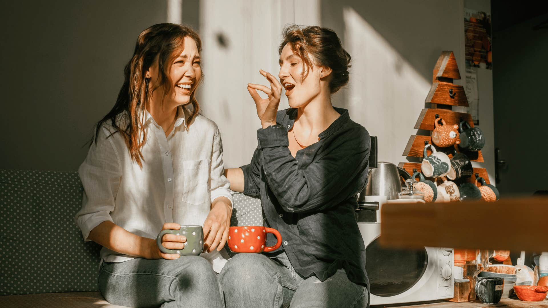 woman in black shirt feeding friend in white shirt as she playfully shows off her good sense of humor