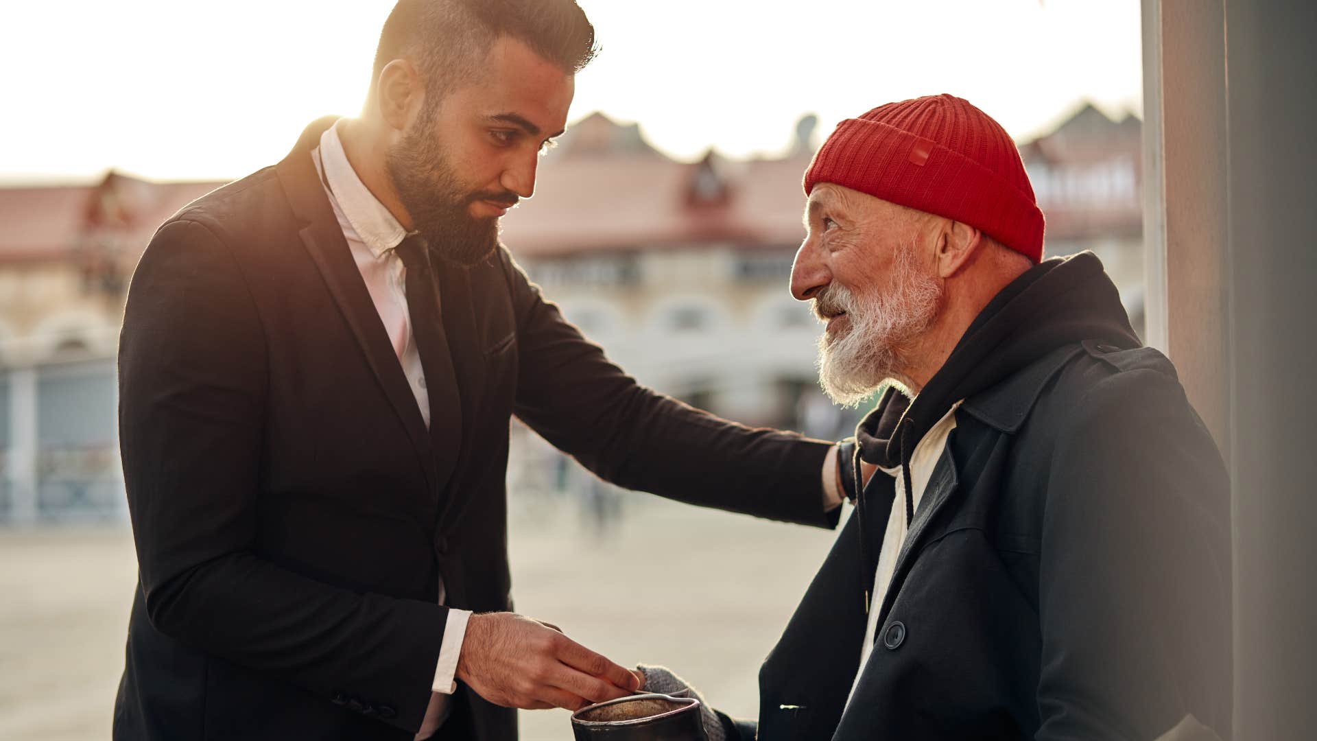 generous man giving money to a homeless man