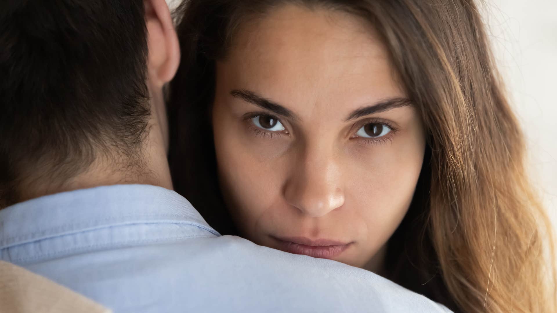 evil woman hugging man looking over his shoulder