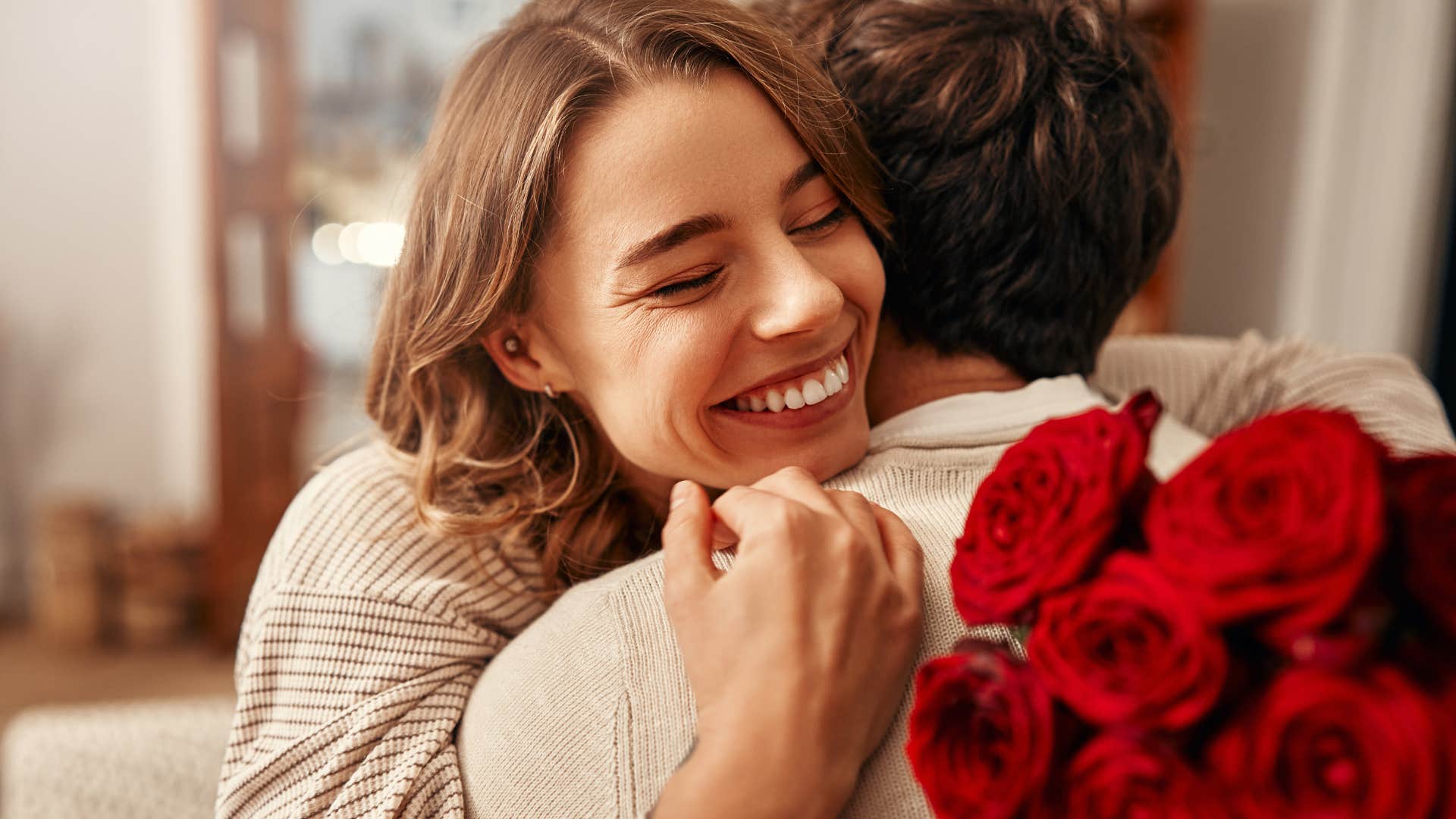 manipulative man hugging his girlfriend giving her flowers