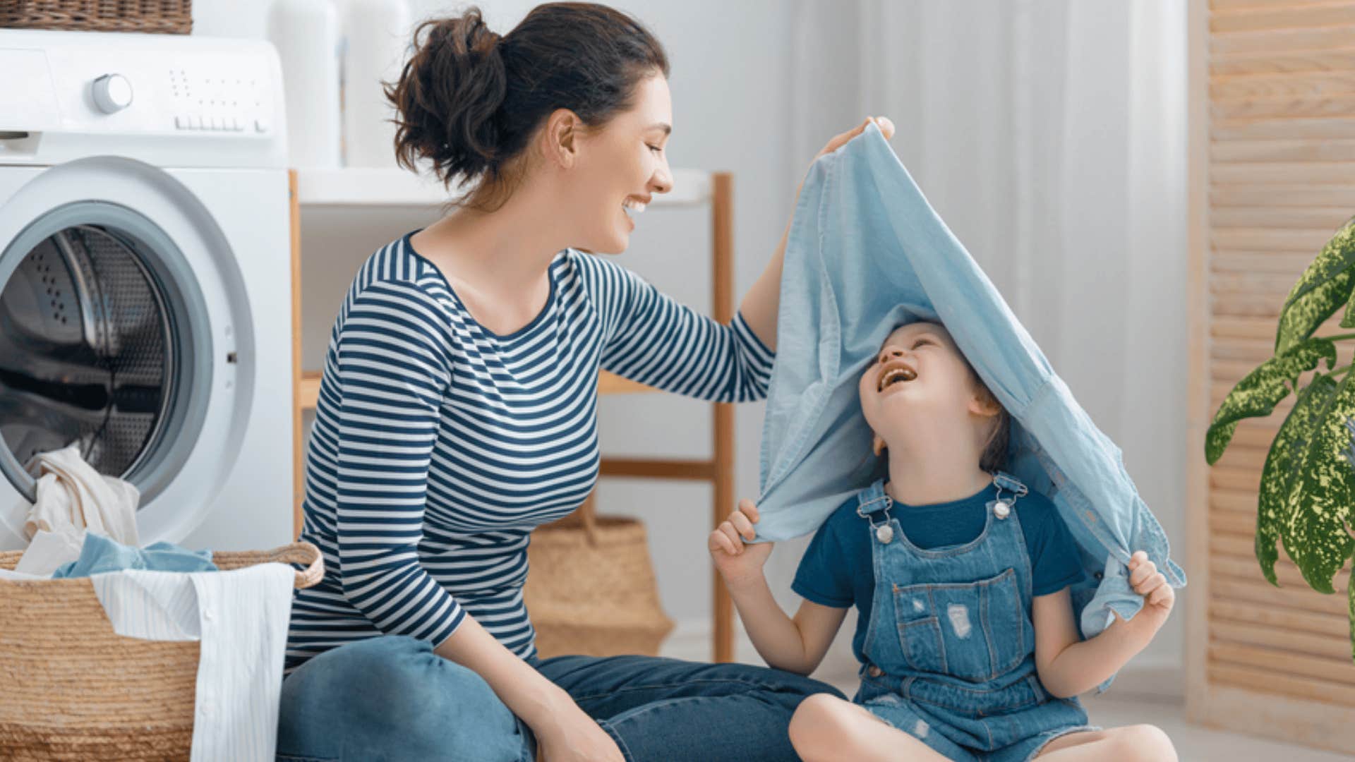 smiling optimistic woman folding laundry with child