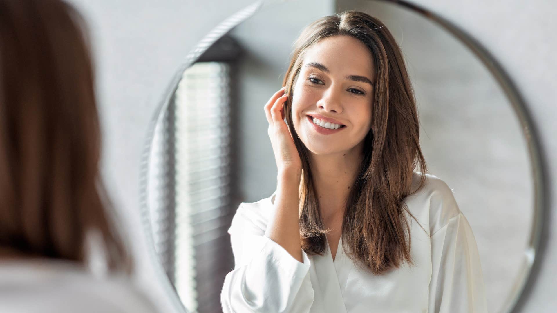 A woman looks into a mirror remembering that it’s her personality not looks that matter.