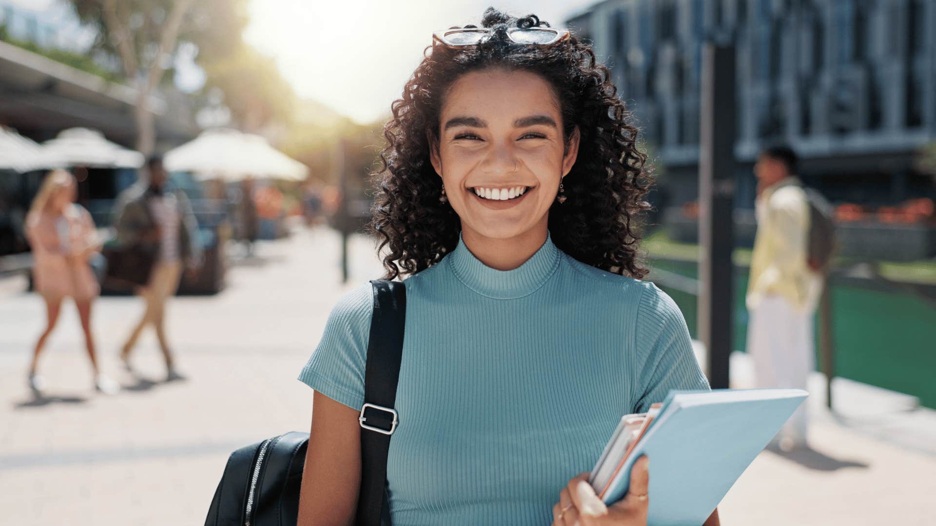 woman smiling while holding books