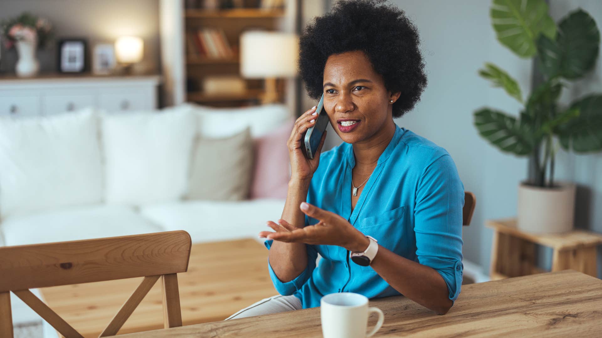woman in blue shirt asking on the phone if it's okay if i bring someone while sitting down