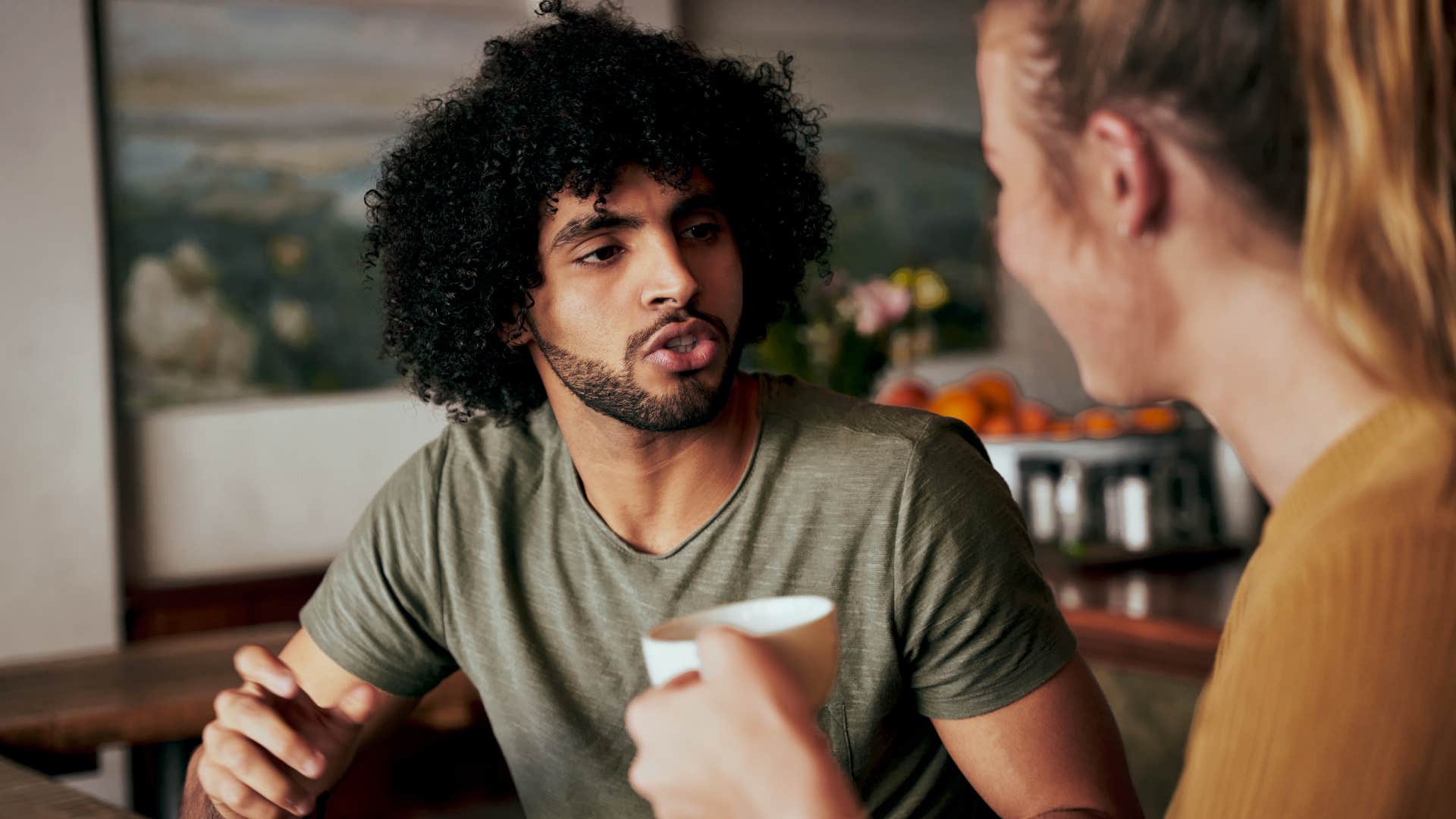 man asking woman in brown shirt if they'll have time to talk or will it be too hectic as she drinks coffee and smiles