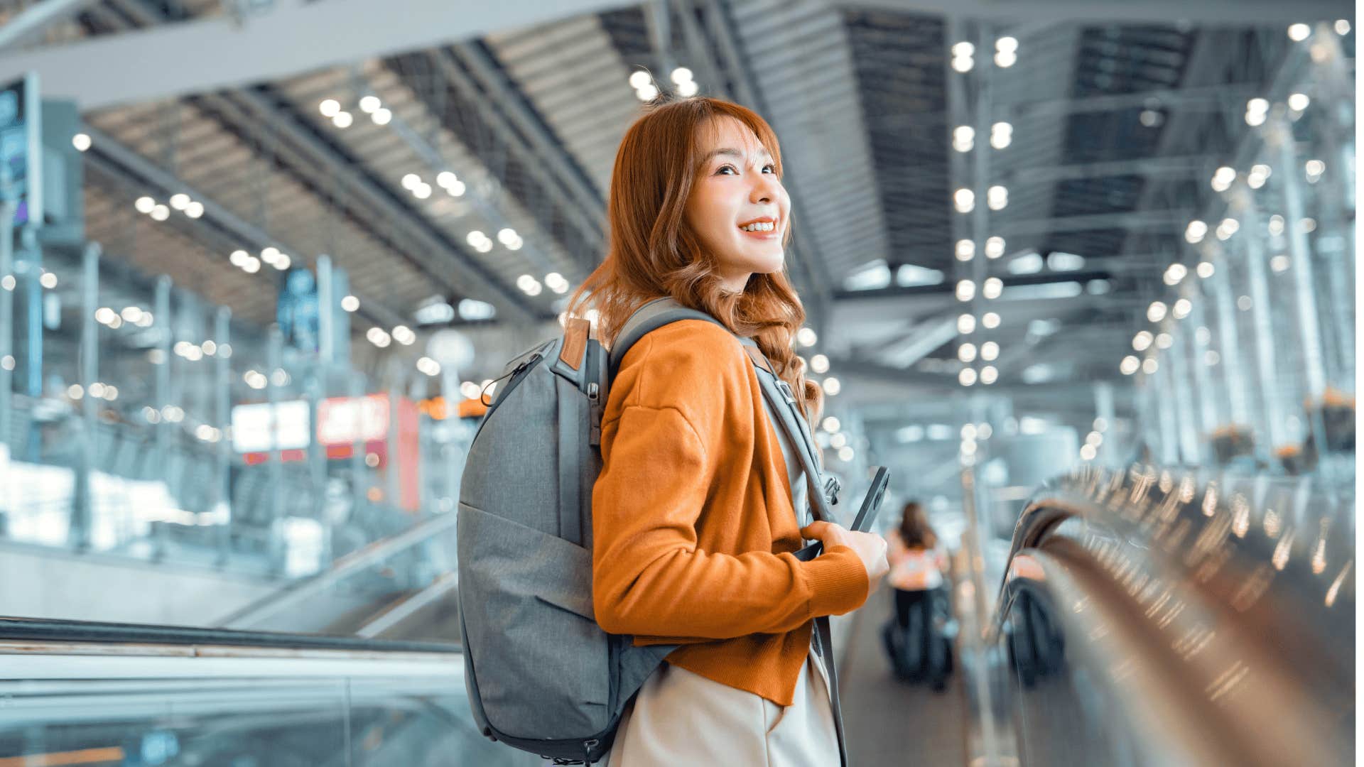 adventurous woman with orange shirt walking through airport