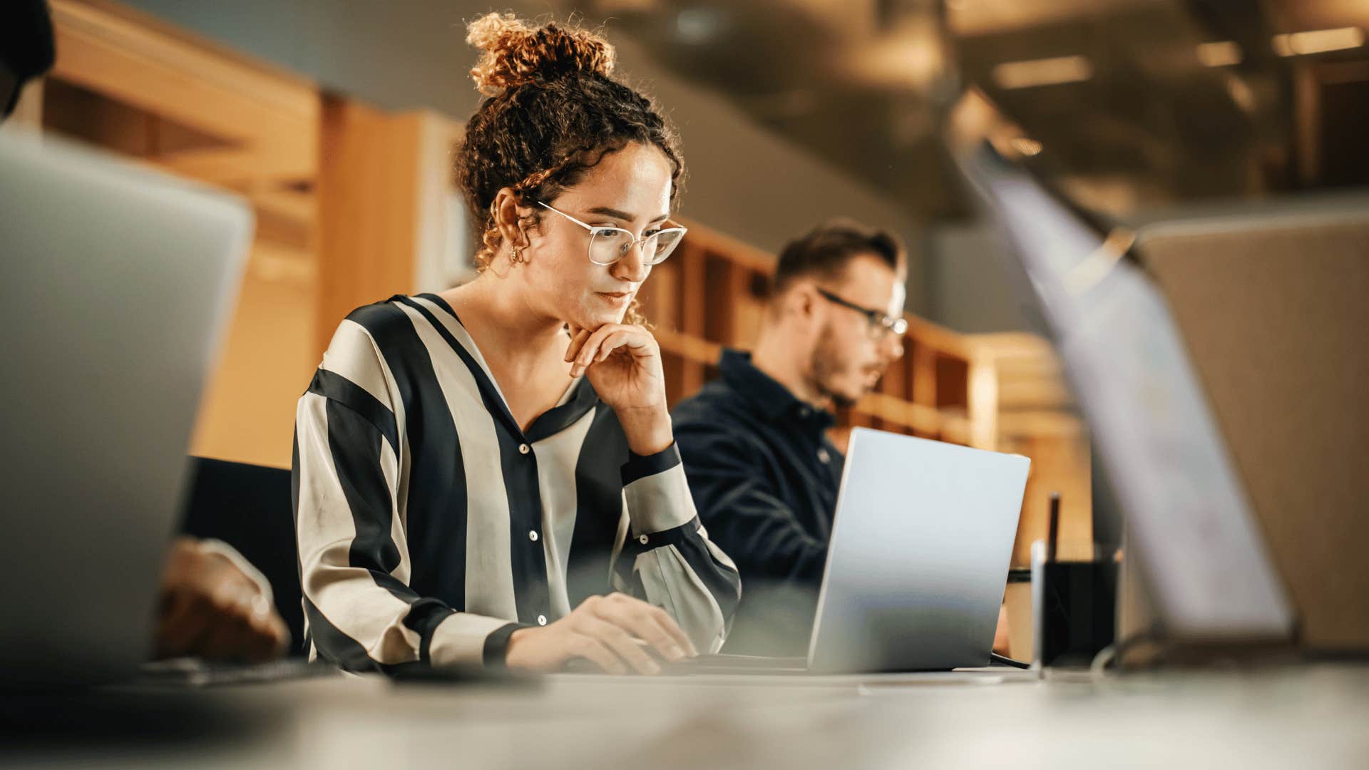busy woman with glasses working on laptop 