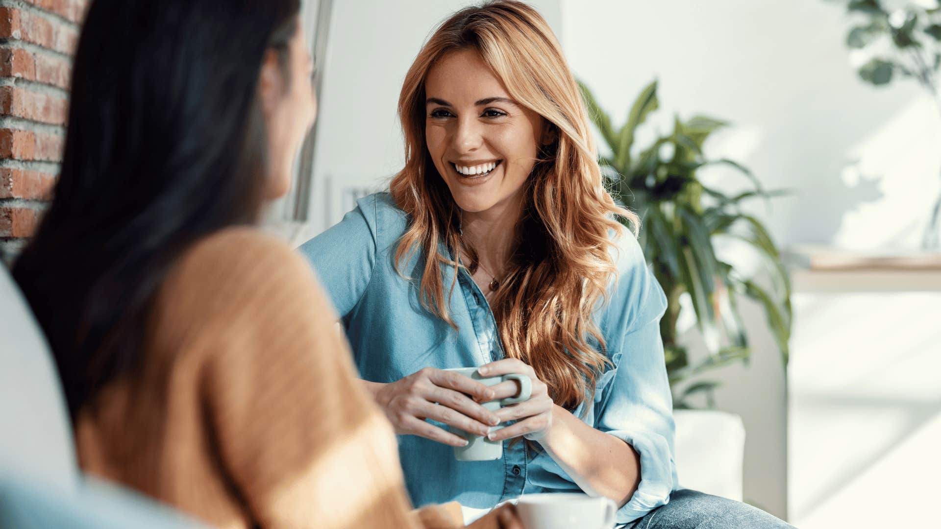 woman whose focused on building strong friendship chatting with friend while drinking coffee and smiling