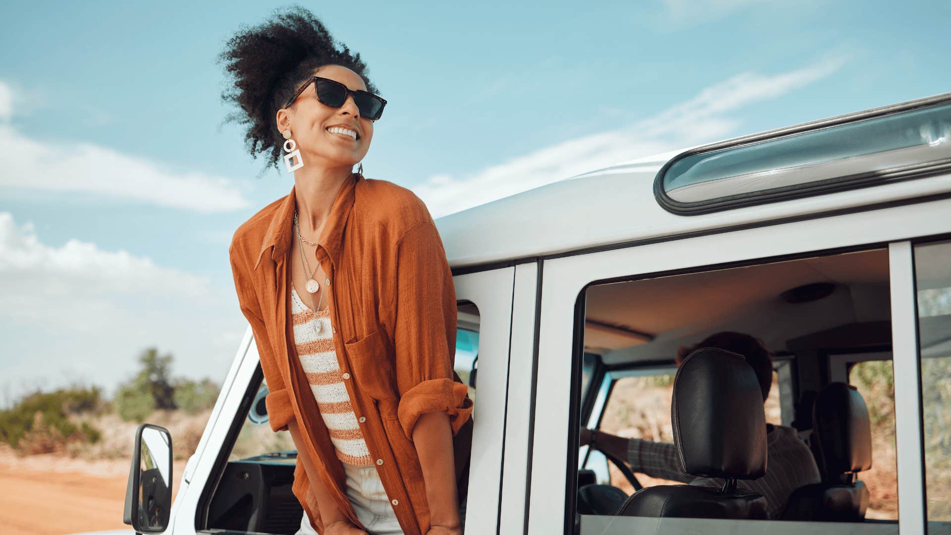 woman whose chasing dreams leaning out the car window and smiling