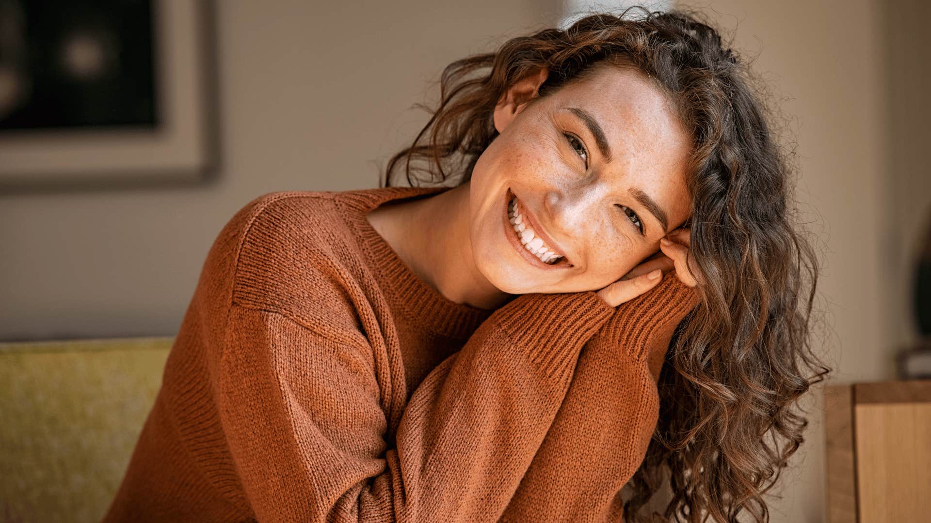 woman with brown sweater who loves herself smiling at the camera