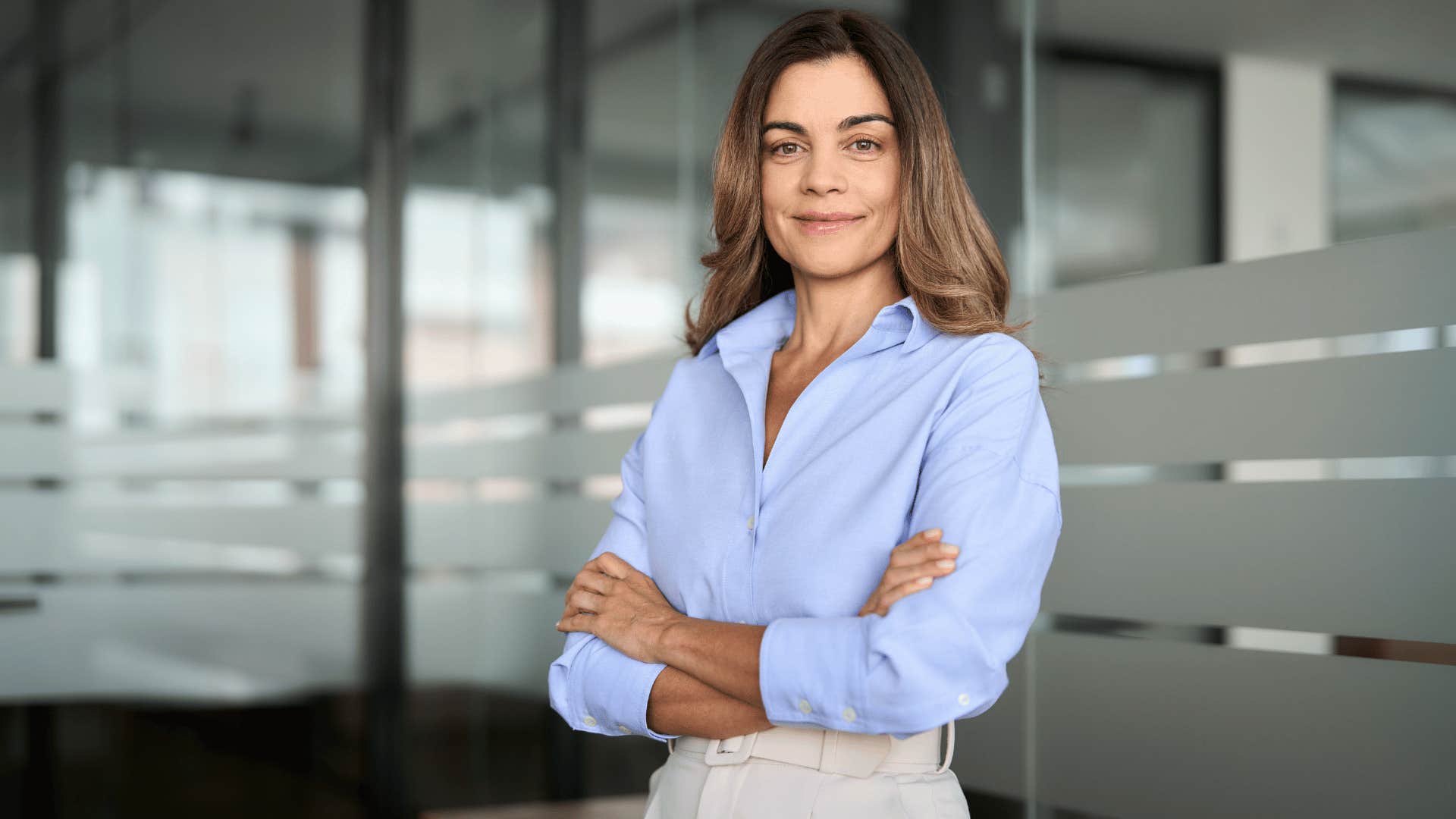 independent woman in blue crossing arms and looking confidently at the camera