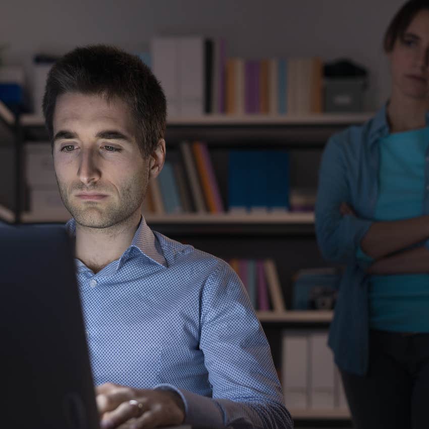 upset woman behind man on computer watching marriage crash
