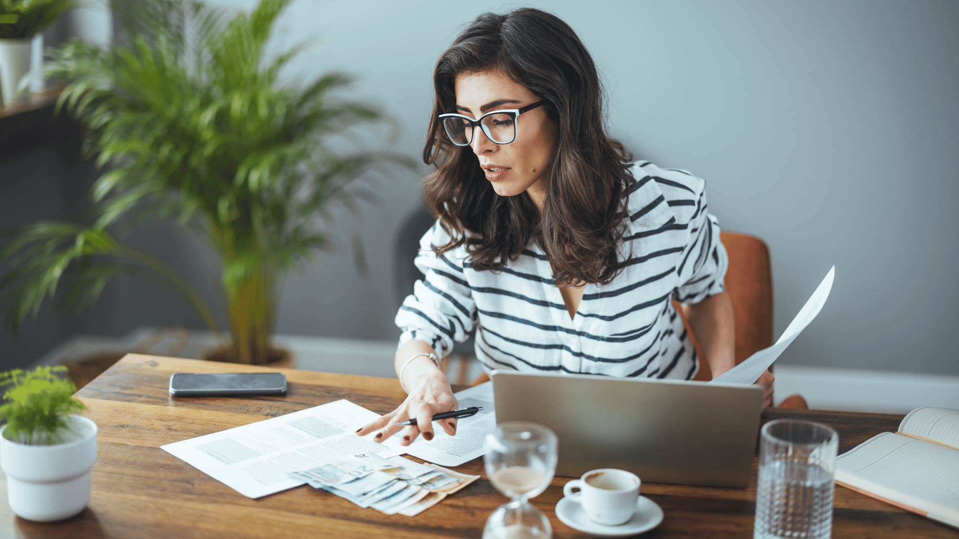 independent woman with glasses and stripped shirt looking at her finances again