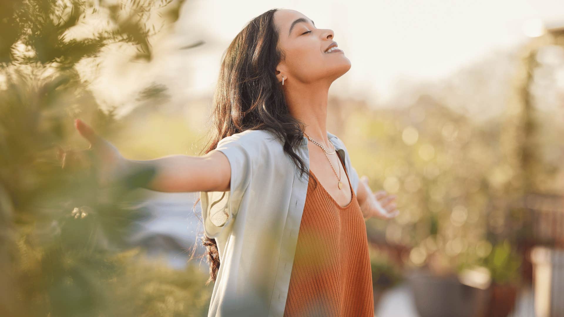woman who has the freedom of being single enjoying the outdoors and deep breathing with her arms behind her