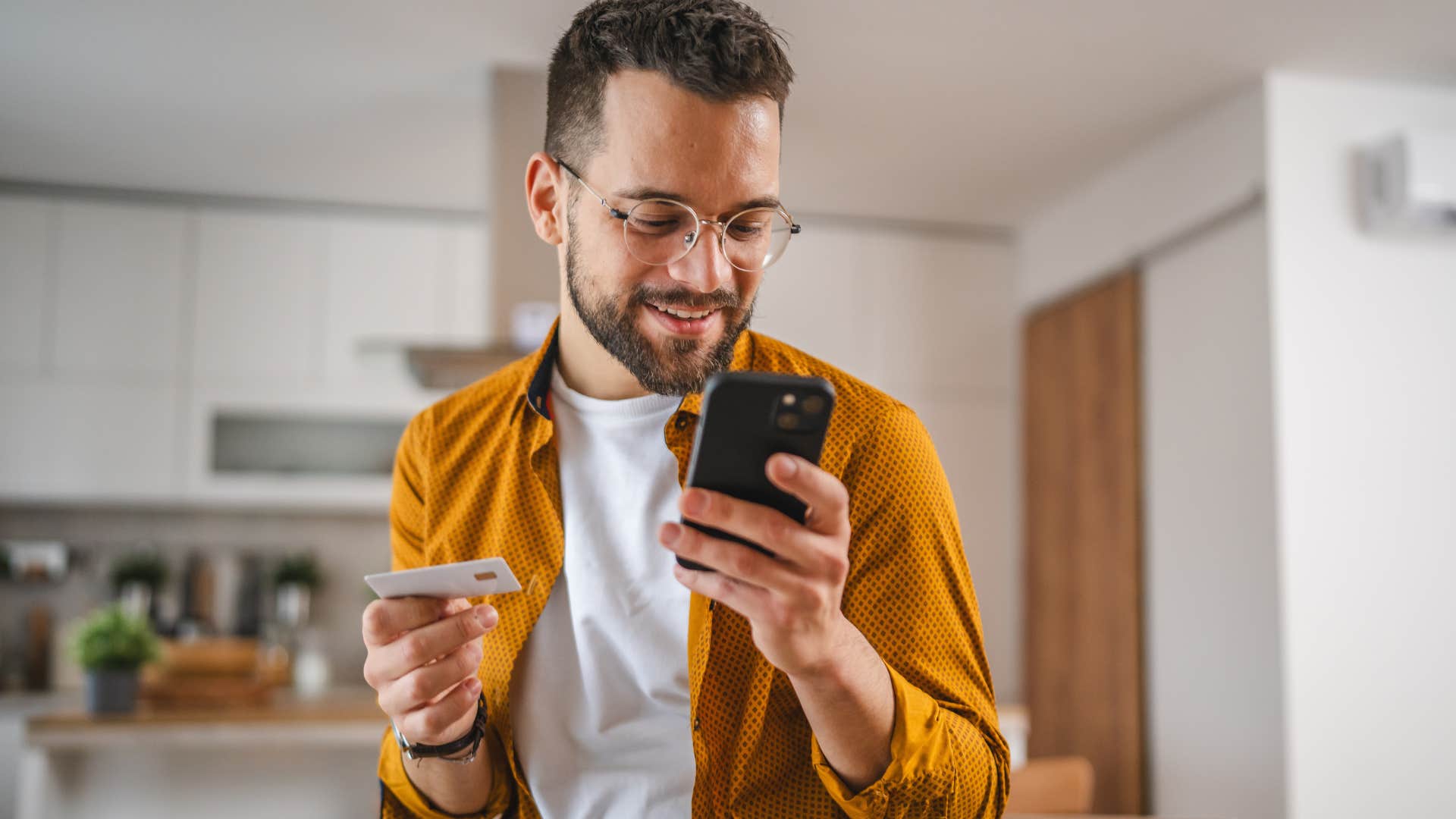 man couponing on his phone while holding his credit card