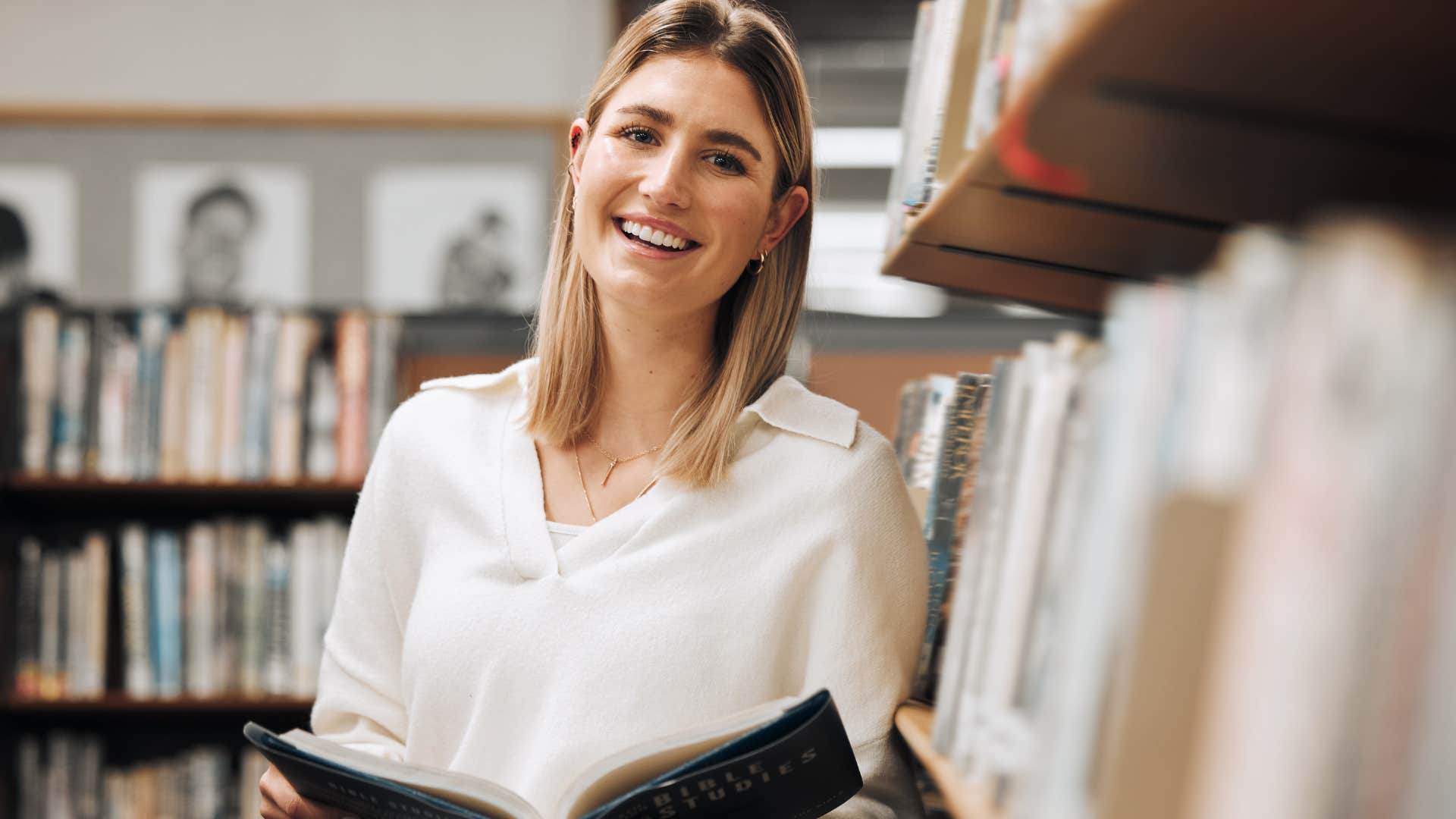 woman smiling reading a book in the library
