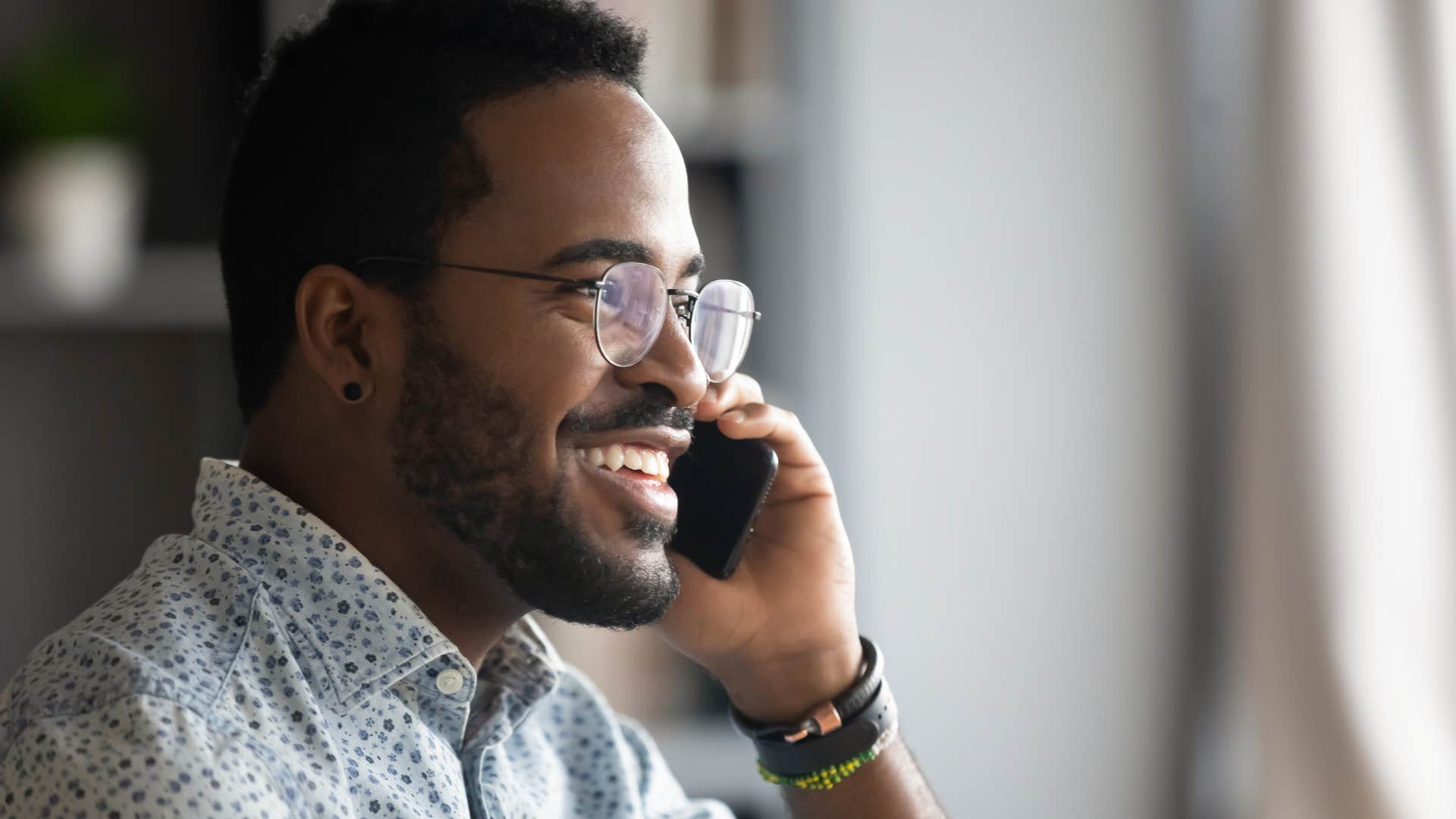 man smiling while negotiating his utility bills on the phone